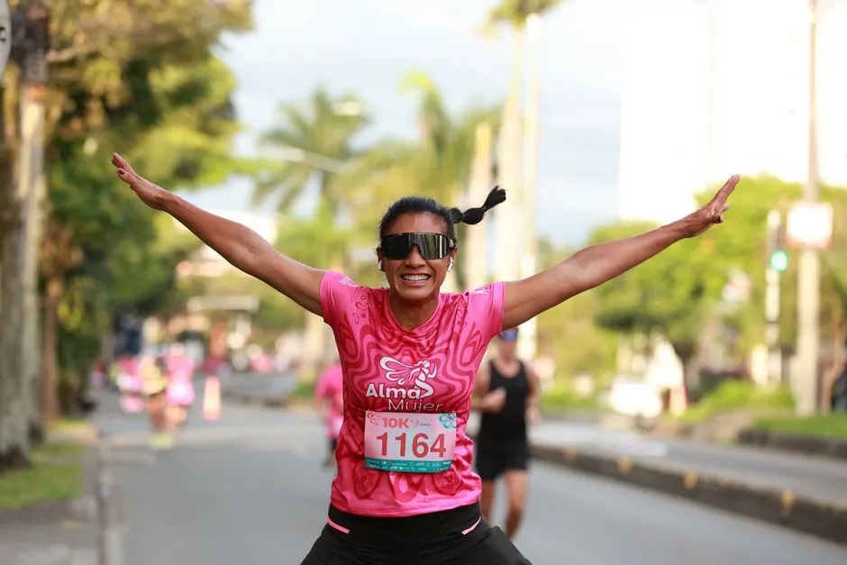 Coureur franchissant la ligne d'un 10 km sur route, chrono visible et public en retrait